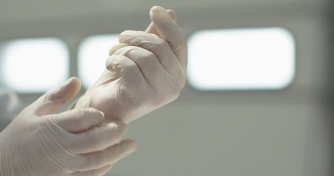 The young man puts on a white latex glove