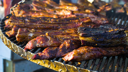 Roasting meat on metal grid over charcoal grill outside