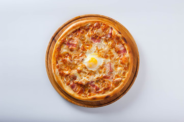 meat pizza lies on a wooden round board on a white background