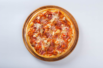 meat pizza lies on a wooden round board on a white background