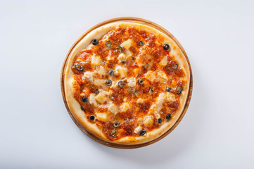 meat pizza lies on a wooden round board on a white background