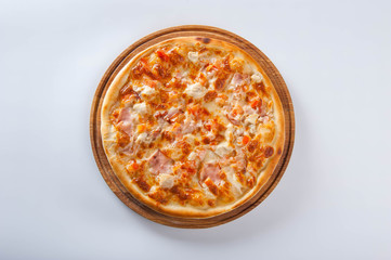 meat pizza lies on a wooden round board on a white background