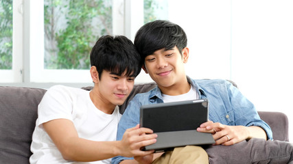 Asian homosexual men smiling with happiness while using digital tablet at home, Happy asia gay couple with  technology lifestyle at home, Friendship, homosexual and lgbt concept