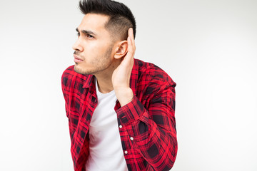 brunette man in a checkered shirt wide open eavesdrops on a conversation on a white studio...