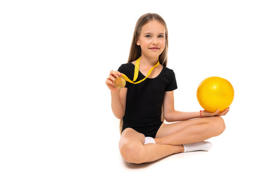 winner girl gymnast sitting on the floor with gymnastic ball on a white background with copy space