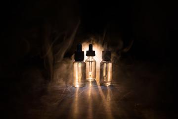 Smoke clouds and vape liquid bottles on dark background. Light effects. Useful as background or vape advertisement or vape background. Selective focus