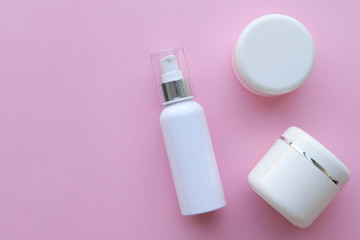 View from above on plastic jars with cream, pink background, space for text