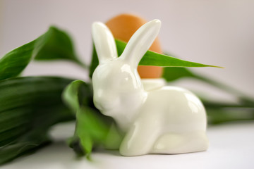 Easter composition ceramic porcelain rabbit bunny salt shaker, egg at eggstand, white background.
