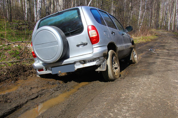 Obraz na płótnie Canvas a grey SUV is towed by a hand winch out of the mud on a forest road