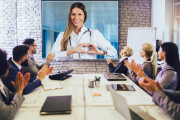 Team of business people looking doctor speech at projector screen in video conference. Doctor...