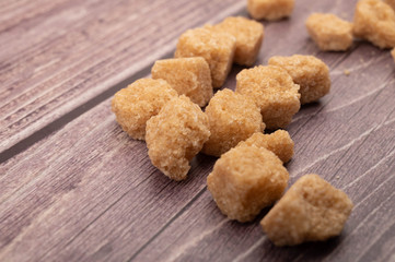 Pieces of brown cane sugar on a wooden background. Close up.