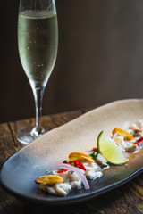 Lubina Ceviche with lime juice, shallots, a wedge of lime and fried garlic