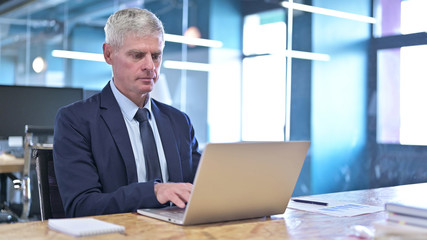 Ambitious Middle Aged Businessman working on Laptop