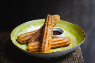 a bowl of churros coated with sugar and served with chocolate sauce
