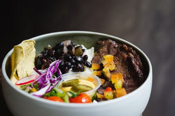 Protein Bowl of grilled Striploin, pilaf rice, beans, guacamole, homemade spiced cheese sauce, jalapenos & corn chips