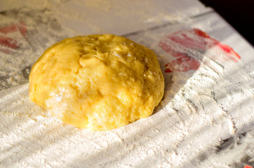 A ball of sweet pastry for shortcake lies on a table sprinkled with flour. Homemade baking. Selective focus.