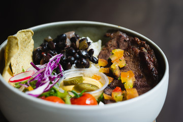 Protein Bowl of grilled Striploin, pilaf rice, beans, guacamole, homemade spiced cheese sauce, jalapenos & corn chips