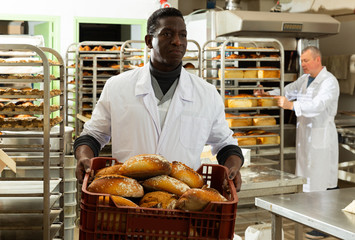 African baker carrying box with baked bread