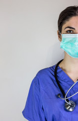 Female doctor in working pajamas with mask for respiratory protection from coronavirus. And stethoscope to visit patient. Blank on the side.