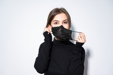 a girl in black clothes putting a black medicinal mask 