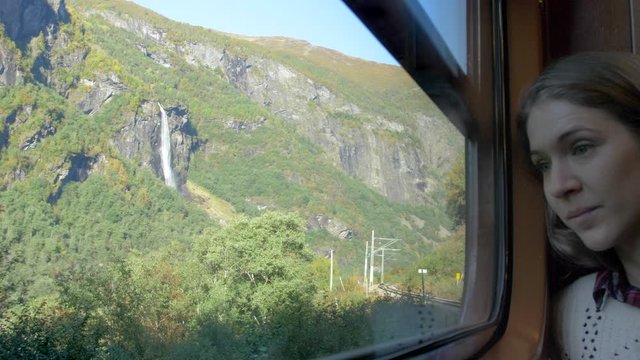 A Woman Taking in an Amazing View of Mountains and Waterfalls from on Board a Train in Norway, Slow Motion