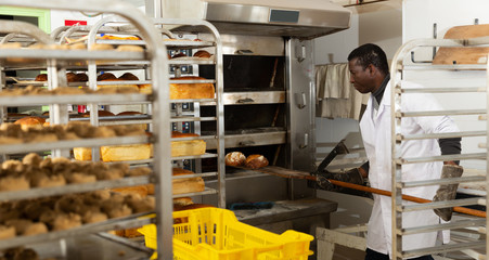 Bakery worker pulls hot bread from the oven