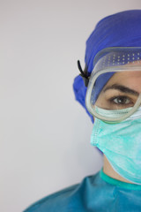 Fototapeta na wymiar Close-up front view of a nurse's face, with a mask, glasses and a surgical cap, to protect against coronavirus.