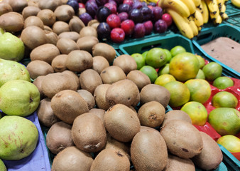 Supermarket display stand with kiwis, pears, oranges, plums and bananas