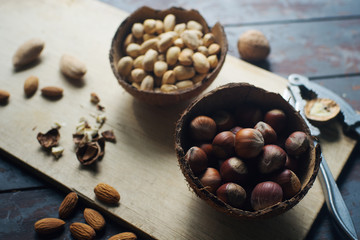 Mix of nuts in coconut bowls on dark wooden table, walnuts, almond, hazelnut, cashew, healthy various superfoods