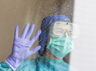 Photo captured from a nurse from below, looking out of a window on a rainy day, with protective equipment for coronavirus