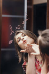 reflection of young woman face in mirror with inscription "I love you", painted heart and lip kiss ,romantic girl send air kiss, concept love and emotions