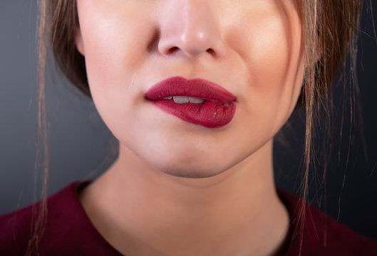 Young beautiful girl bits her lip, macro detail. Woman in love. Desire. Botton half of female face close-up