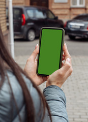Smartphone with a blank screen in the hands of a girl on the street