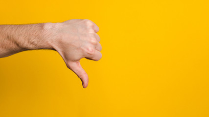 not good and not approved. close up hand of a man showing thumb down dislike sign over yellow...