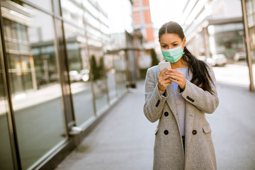 Fototapeta premium Pretty young woman with protective facial mask on the street