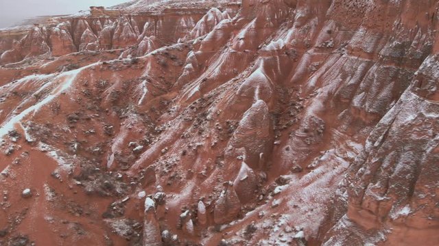 Cinematic aerial view of snowy landscape at Devrent Valley in Cappadocia. Fairy chimneys surronded by snow in Imaginary valley full of unique tuff rock formations in winter season in Cappadocia. 