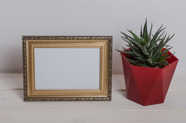 Mock up frame on a white wooden table with cactus in the room.