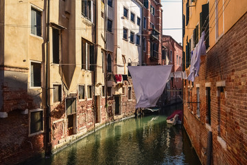 Fototapeta na wymiar Canal between old houses in the historical part of Venice on a sunny day.