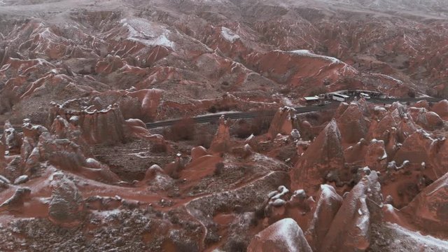 Cinematic aerial view of snowy landscape at Devrent Valley in Cappadocia. Fairy chimneys surronded by snow in Imaginary valley full of unique tuff rock formations in winter season in Cappadocia. 