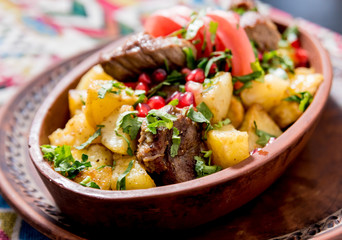 Fried potatoes with pieces of meat in a clay pot. European cuisine.