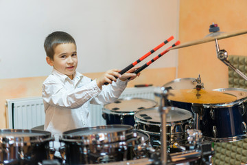 Boy drumming. boy in a white shirt plays the drums. A boy in a white shirt is drumming