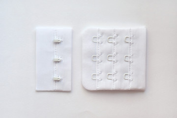 Hooks and loops for a bra on a white piece of fabric. Metal fasteners for women's underwear....