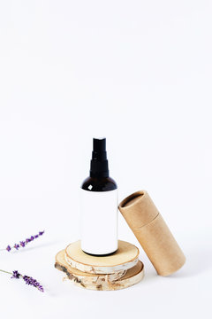Glass spray bottle standing on wooden stands and craft tube next to, lavender twigs.