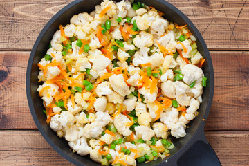 Step by step preparation of vegetable stew with cauliflower, step 3 - adding cauliflower, beans to the pan, top view, selective focus