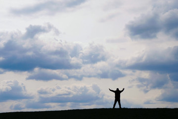 Silhouette of a man on a hill on a background of clouds in Ukraine. Changing the philosophy of life concept. Self-isolation concept.