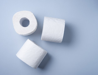 three rolls of white toilet paper on a blue background. Pandemic, covid-19, essential goods, scarcity