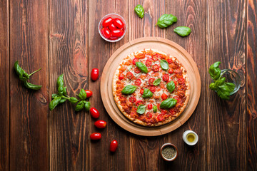 Delicious pizza with tomatoes and basil on wood.