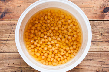 Cooked chickpeas in a pan with water on a wooden table, top view, selective focus