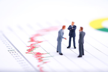 Fototapeta premium Miniature people:Businessman standing with team and discuss on the stock trend with copy space. Financial crisis. Data analysis. Stock market volatility risk. Information for investment.