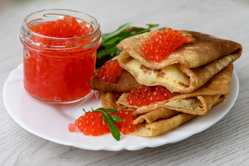 Pancakes with red caviar on a white plate. close-up